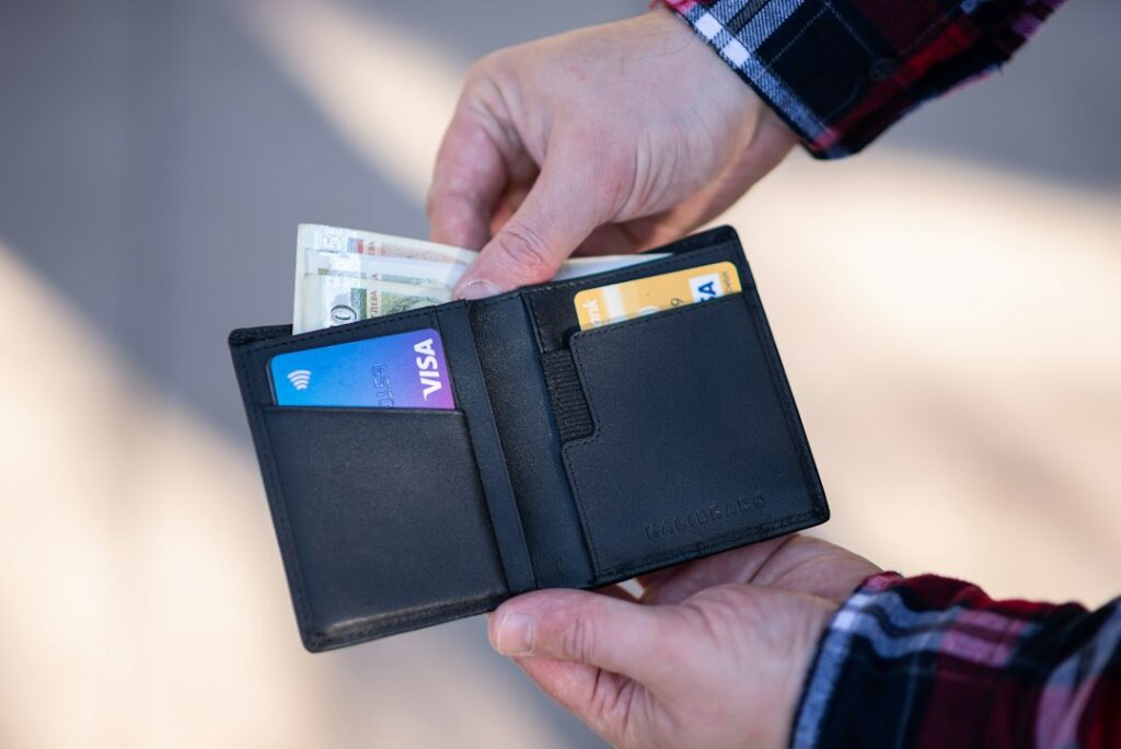Black leather bifold wallet held in hand, a common style from premium wallet brands