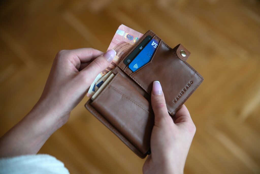 Hand holding a brown leather card wallet with a few cards inside