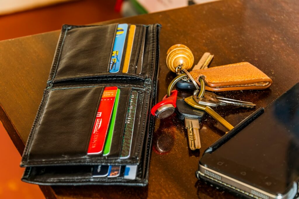 Leather wallet, keys and phone on a wooden table, the everyday carry most men take out each day